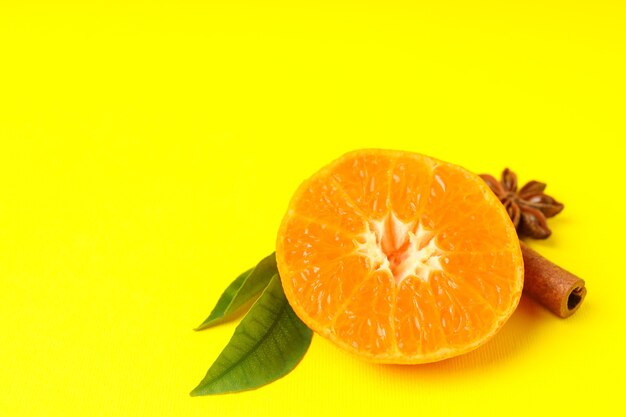 Mandarin with leaves and cinnamon on yellow background