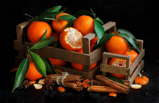 Mandarins in a basket and spices on a dark background