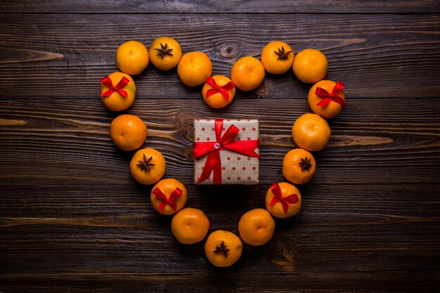 Mandarins in the form of hearts on wooden background with gifts