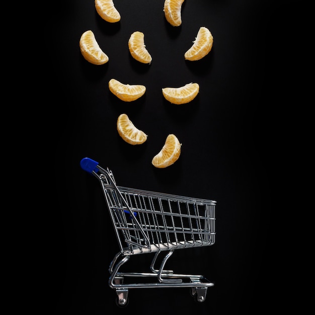 Mandarins and shopping cart on a black background