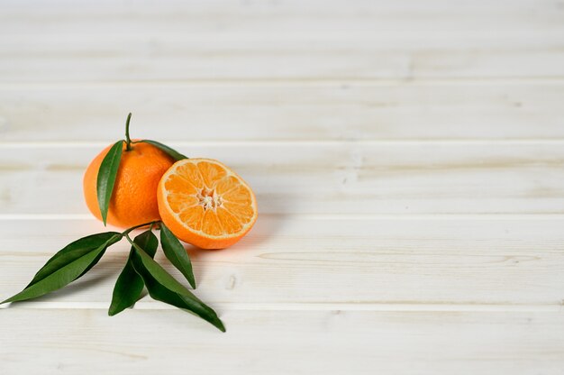 Mandarins with leaves on the white wooden background.