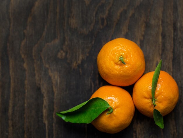 Mandarins with leaves on a wooden background, top view