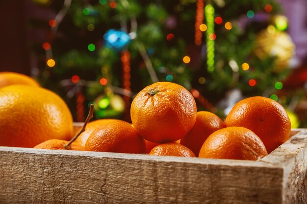 Mandarins in wooden box with christmas tree.