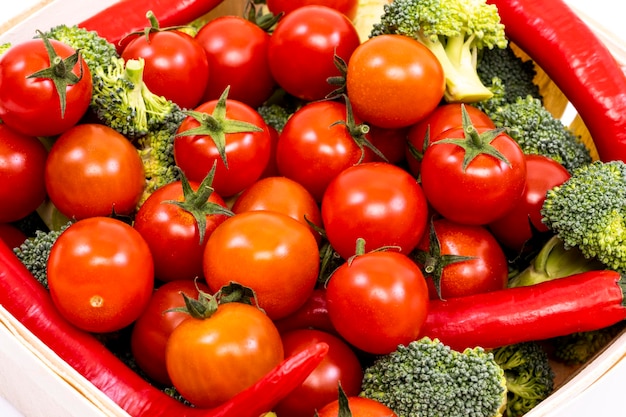 Mandje met stukjes verse cherrytomaatjes, broccoli en roodgloeiende chilipepers