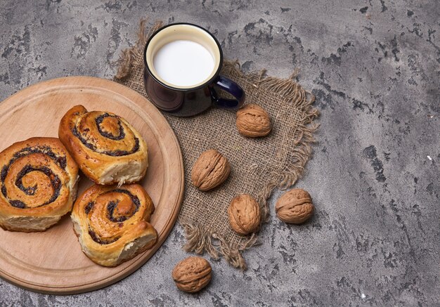 Mandje met zelfgemaakte broodjes met jam, geserveerd op oude houten tafel met walnoten en kopje melk