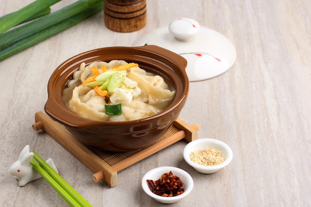 Mandu Guk, Korean Dumpling Soup with Spring Onion Topping and Sliced Fried Egg, Served with Chilli Flakes and Sesame Seed