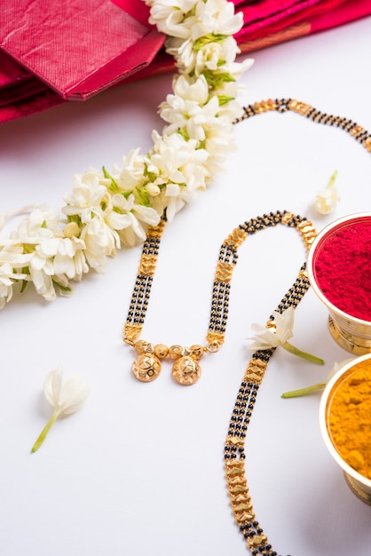 Mangalsutra or Golden Necklace to worn by a married hindu women, arranged with traditional saree  with huldi kumkum and mogra flowers gajra, selective focus