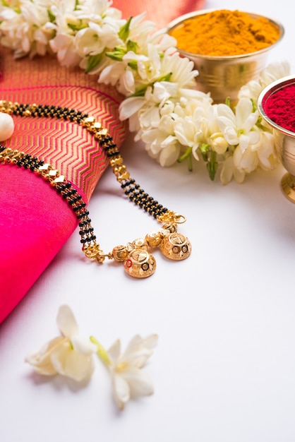 Мангалсутра или Золотое ожерелье для замужних индуистских женщин, украшенное традиционным сари с хульди кумкум и цветами могры гаджра, выборочный фокус