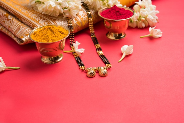 Photo mangalsutra or golden necklace to worn by a married hindu women, arranged with traditional saree  with huldi kumkum and mogra flowers gajra, selective focus