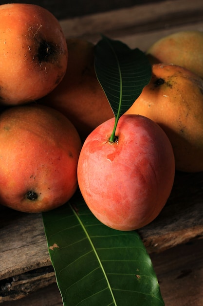 Mangga Gedong Gincu - Rijp van Mango Varian, meestal gekweekt in Majalengka en Cirebon, West-Java. Gedong Gincu Mango heeft een rode schil en een geurig aroma. Op rustieke houten plank