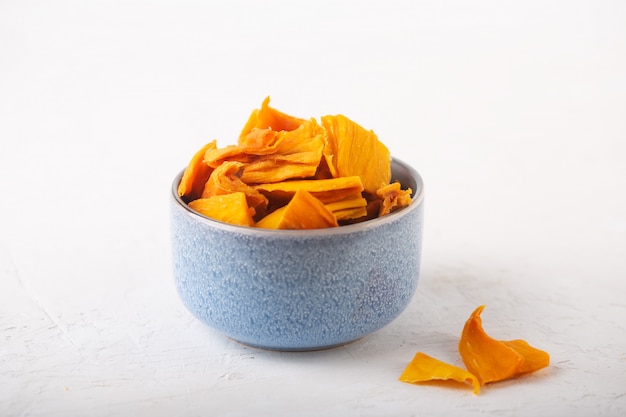 Mango chips in a blue bowl on a white background