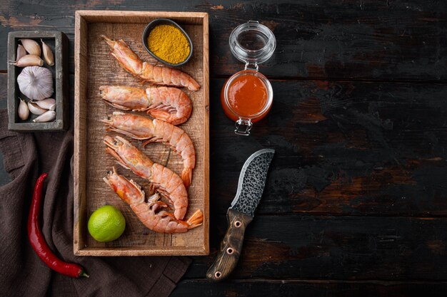 Chutney di mango grande guscio crudo su ingredienti di gamberoni crudi impostati, in scatola di legno, sul vecchio tavolo di legno scuro