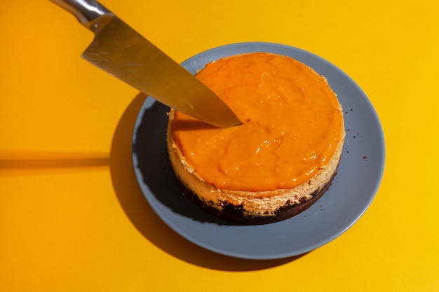 Foto mango en duindoorn zelfgemaakte cheesecake op gele achtergrond.