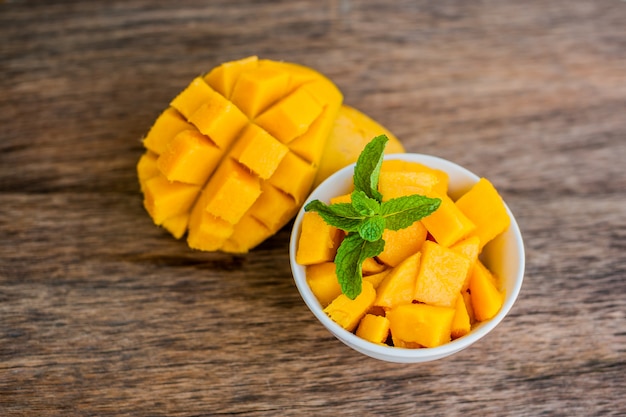 Mango fruit and mango cubes on the wooden table.