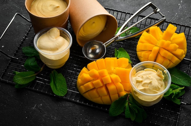 Mango-ijs met munt en verse mango-ijslepel Op een zwarte stenen achtergrond bovenaanzicht