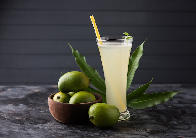 Сок манго OR Aam Panna или Panha в прозрачном стакане с целыми зелеными фруктами, выборочный фокус