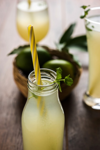 Mango juice OR Aam Panna or Panha in a transparent glass with whole green fruit, selective focus