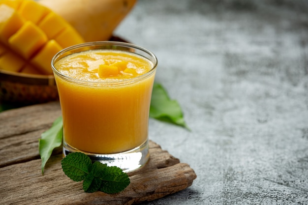 Photo mango juice in the glass on dark surface