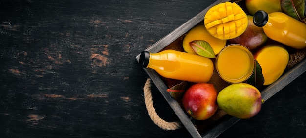 Mango e succo in una scatola di legno su uno sfondo di legno frutti tropicali vista dall'alto spazio libero per la copia