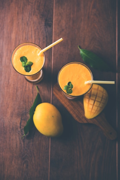 Mango Lassi or yogurt, Indian popular summer drink served in glass with whole Alphonso Aam fruit, selective focus