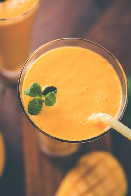 Mango Lassi or yogurt, Indian popular summer drink served in glass with whole Alphonso Aam fruit, selective focus