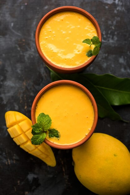 Mango Lassi or yogurt, Indian popular summer drink served in glass with whole Alphonso Aam fruit, selective focus