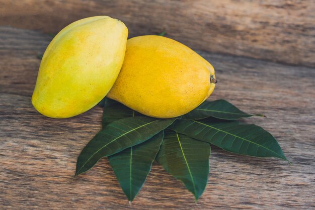 Mango and mango leaves on an old wooden background