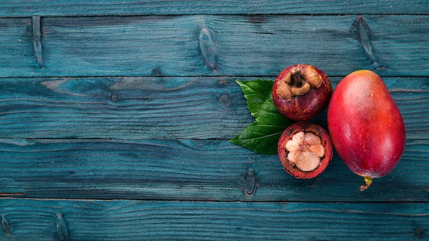 Mango and mangosteen. Fresh Tropical Fruits. On a wooden background. Top view. Copy space.