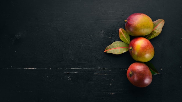 Mango met bladeren op een zwarte houten achtergrond Tropische vruchten Bovenaanzicht vrije ruimte voor uw tekst