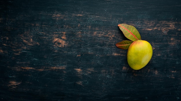 Mango met bladeren op een zwarte houten achtergrond Tropische vruchten Bovenaanzicht vrije ruimte voor uw tekst