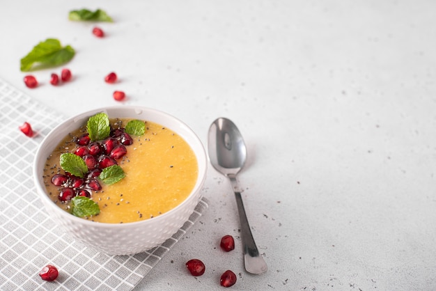 Mango and pomegranate smoothie with mint leaves in a gray bowl