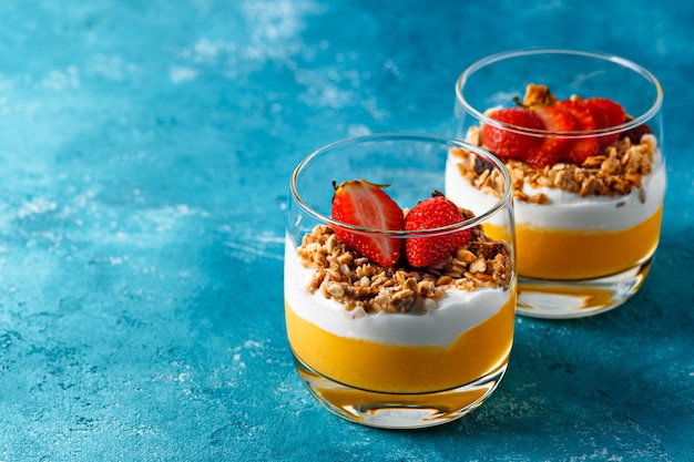 Mango puree dessert met kwark en granola versierd met aardbeien