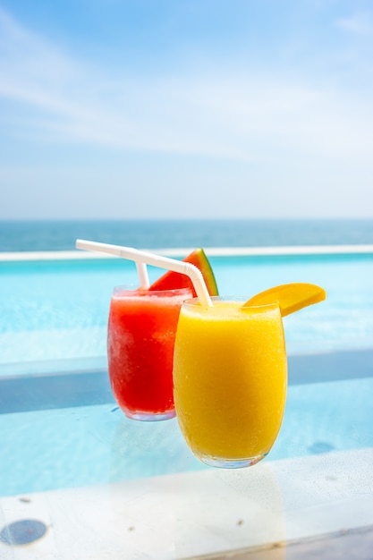 mango smoothie en watermeloen smoothie met zwembad en zee strand achtergrond