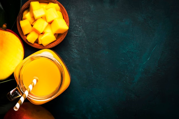 Mango smoothie in glass jar with fresh fruit on blue background copy space top view