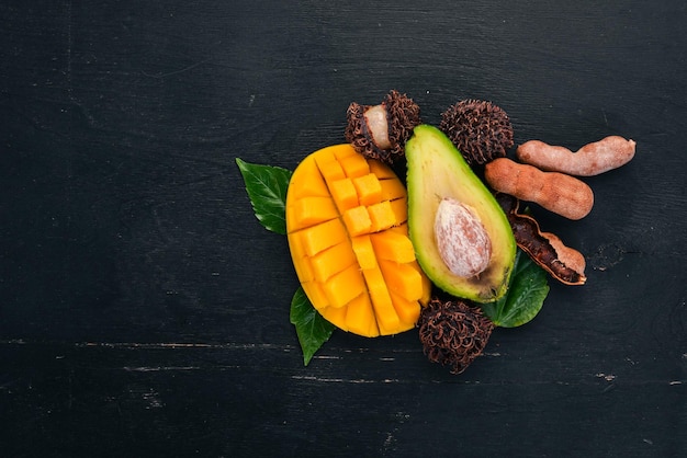 Mango tamarind avocado and rambutan Fresh Tropical Fruits On a wooden background Top view Copy space