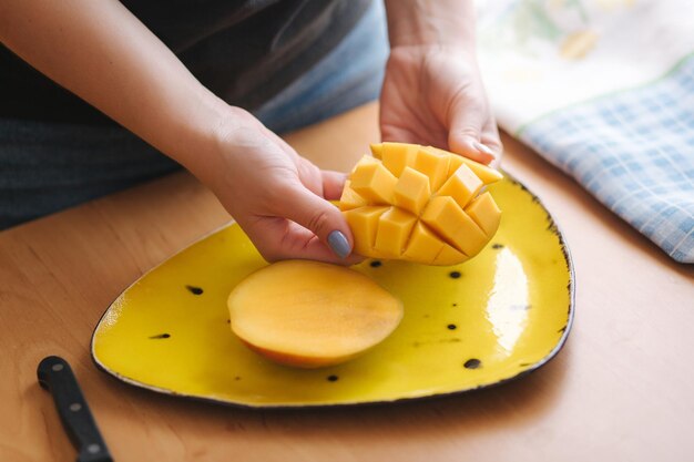 Foto mango van de vrouwenplak op gele plaat vers exotisch fruit