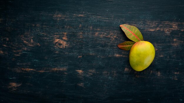 Mango with leaves on a black wooden background Tropical Fruits Top view free space for your text