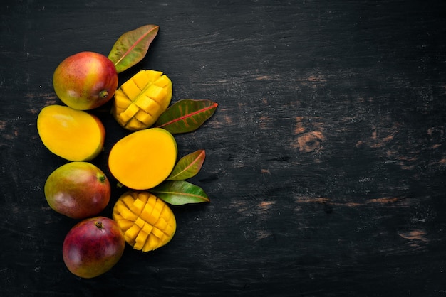 Mango with leaves on a black wooden background Tropical Fruits Top view free space for your text