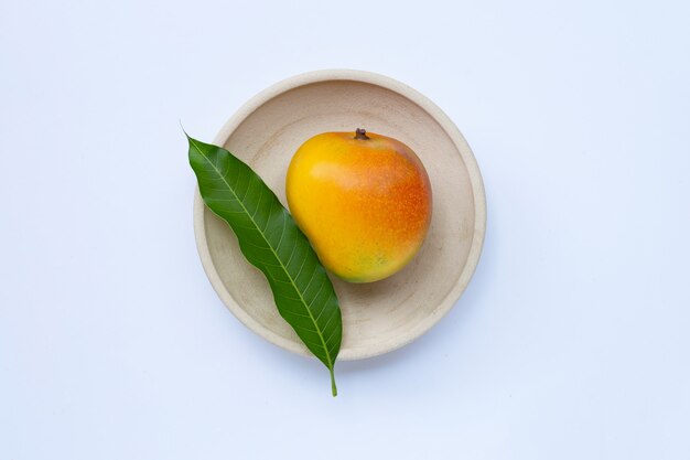 Mango with leaves in a white bowl