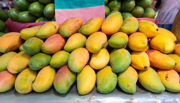 Mangoes are stacked on a table in a market.