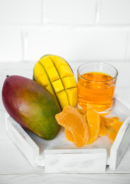 Mangoes and oranges on a white wooden table with juice