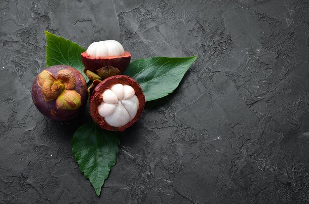 Mangosteen met een blad op een zwarte stenen achtergrond Tropisch fruit Bovenaanzicht Vrije ruimte voor tekst