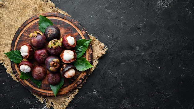 Mangosteen with a leaf on a black stone background Tropical Fruits Top view Free space for text