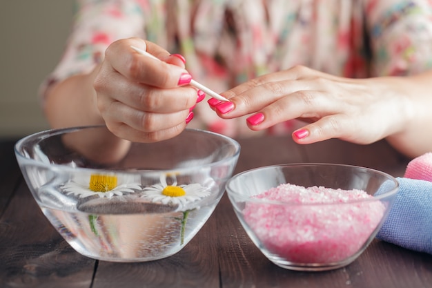 Manicure applying, cleaning the cuticles with wooden stick