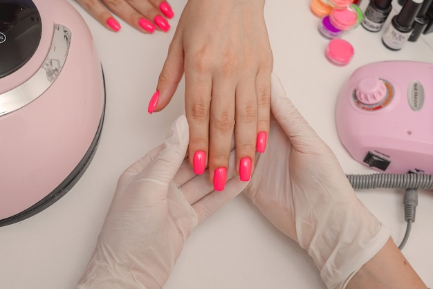 Manicure belle unghie femminili ben curate con smalto rosa brillante nel salone