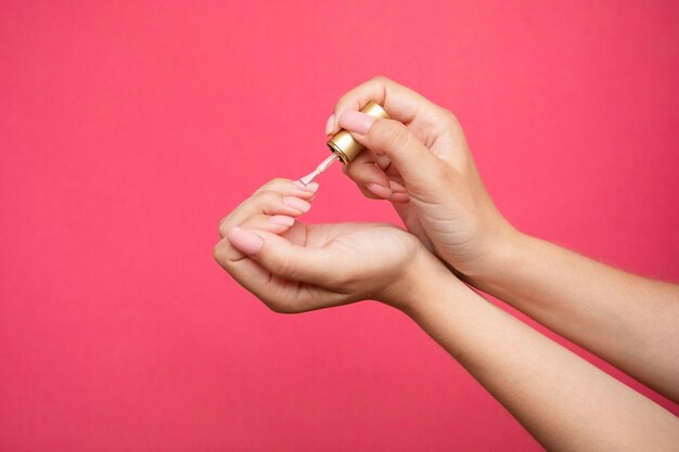 Маникюрная щетка носит лак для ногтей. Маникюр с розовыми блестками.
