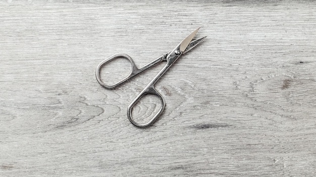 Manicure cuticle scissors on laminate flooring that looks like white wood table.
