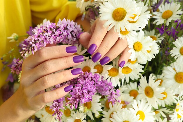 Manicure design with a matte lilac coating over a bouquet of daisies.