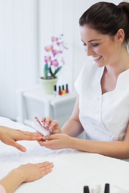 Manicure die spijkerborstel op de spijkers van de vrouw gebruikt