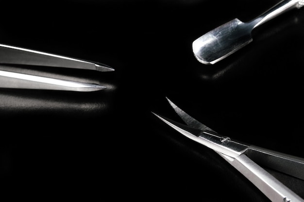 Manicure en pedicure tools op zwarte achtergrond Nagelvijl schaar pincet pusher tangen kwasten Medische hulpmiddelen bovenaanzicht
